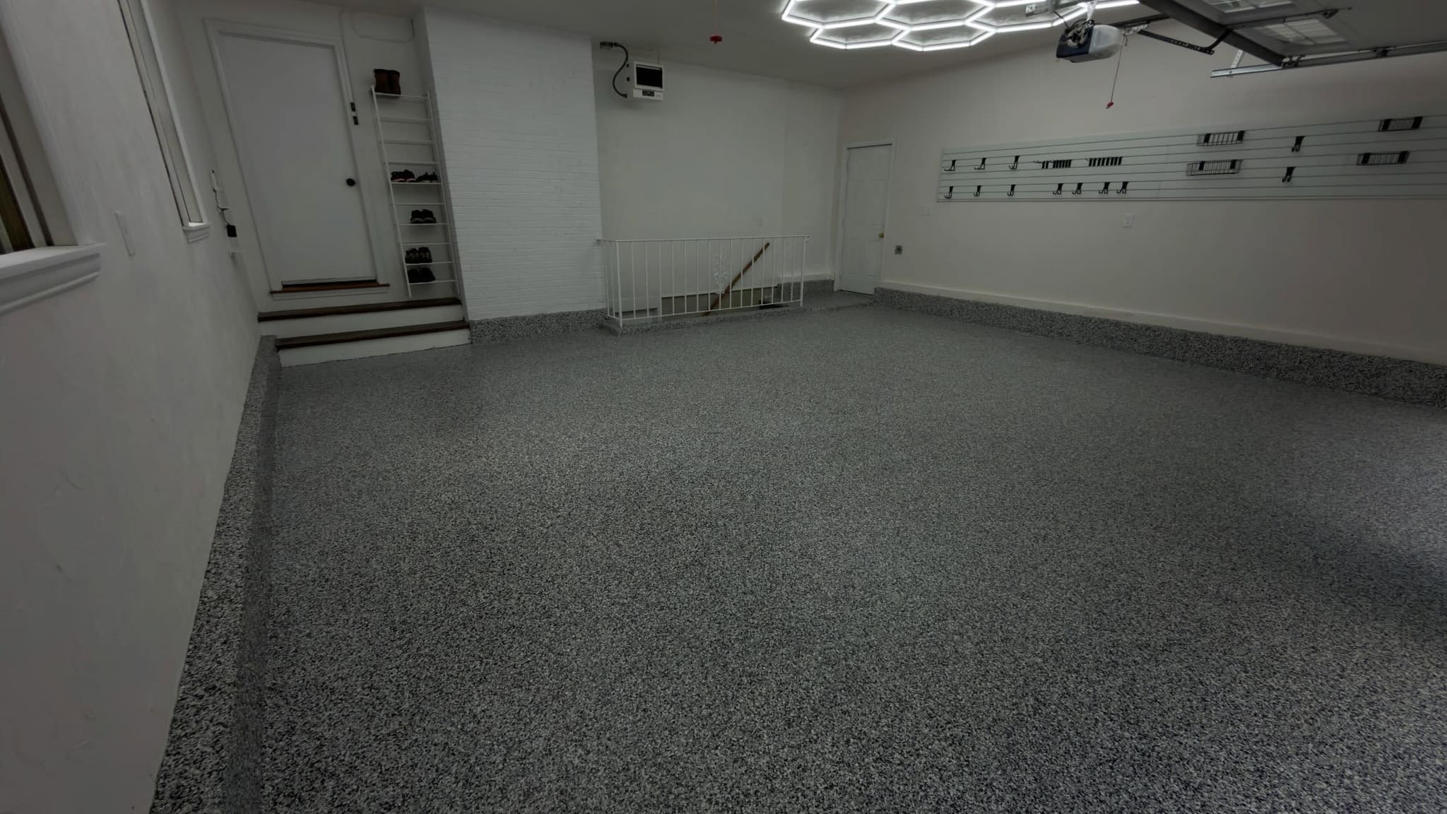 Garage with a uniform grey flake epoxy floor under hexagonal lighting